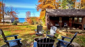 A cabin with a deck, two Adirondack chairs, and a fire pit.