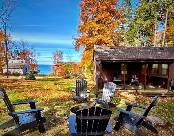 A cabin with a deck, two Adirondack chairs, and a fire pit.