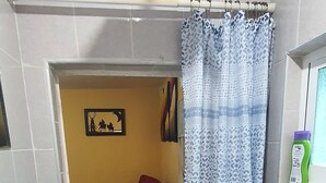 Un baño con ducha, lavamanos, un tapete rojo y cortina de baño.
