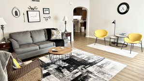 A modern living room with a grey sofa, a round coffee table, a yellow armchair, and a patterned rug. - Historic District, Downtown, STE 1 (Rapid City)
