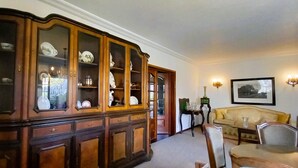 A traditional room with a wooden cabinet, a green chair, a yellow sofa, and a framed picture on the wall. - Moradia Entre o mar e a ria (Gafanha da Nazaré)