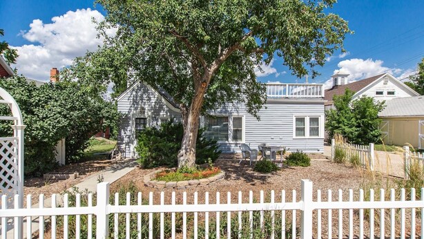 A residential property with a white picket fence, a large tree in the front yard, and a house with a number '1018' on the side. - Historic District, Downtown, STE 3 (Rapid City)