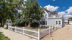 A two-story house with a white picket fence, a covered patio, and a driveway. - Historic District, Downtown, STE 3 (Rapid City)