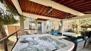 A hot tub with a wooden deck and outdoor furniture, surrounded by a wooden fence and trees. - Clockers House at Galway - 3 bedroom, 3 bath luxury home on-site of Galway Downs (Temecula)