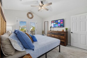 A bedroom with a bed, a dresser, a TV, and a ceiling fan.