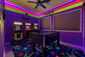 A room with a foosball table, arcade games, and a star-patterned floor.