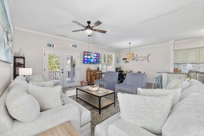 A living room with a sofa, armchairs, a coffee table, a TV, and a ceiling fan.
