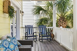 A porch with two rocking chairs, a bench, and a dog.