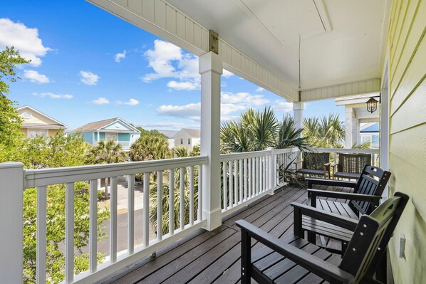 A covered porch with wooden furniture and a view of neighboring houses.