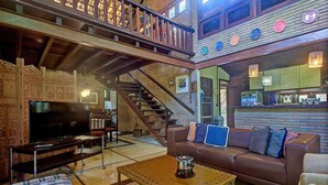 A spacious living area with a large television, a brown leather sofa, and a wooden coffee table. - Casa na Serra de Mulungu por Carpediem (Mulungu)