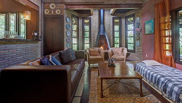 A cozy interior with a brick wall, a fireplace, and a seating area with a sofa and chairs. - Casa na Serra de Mulungu por Carpediem (Mulungu)