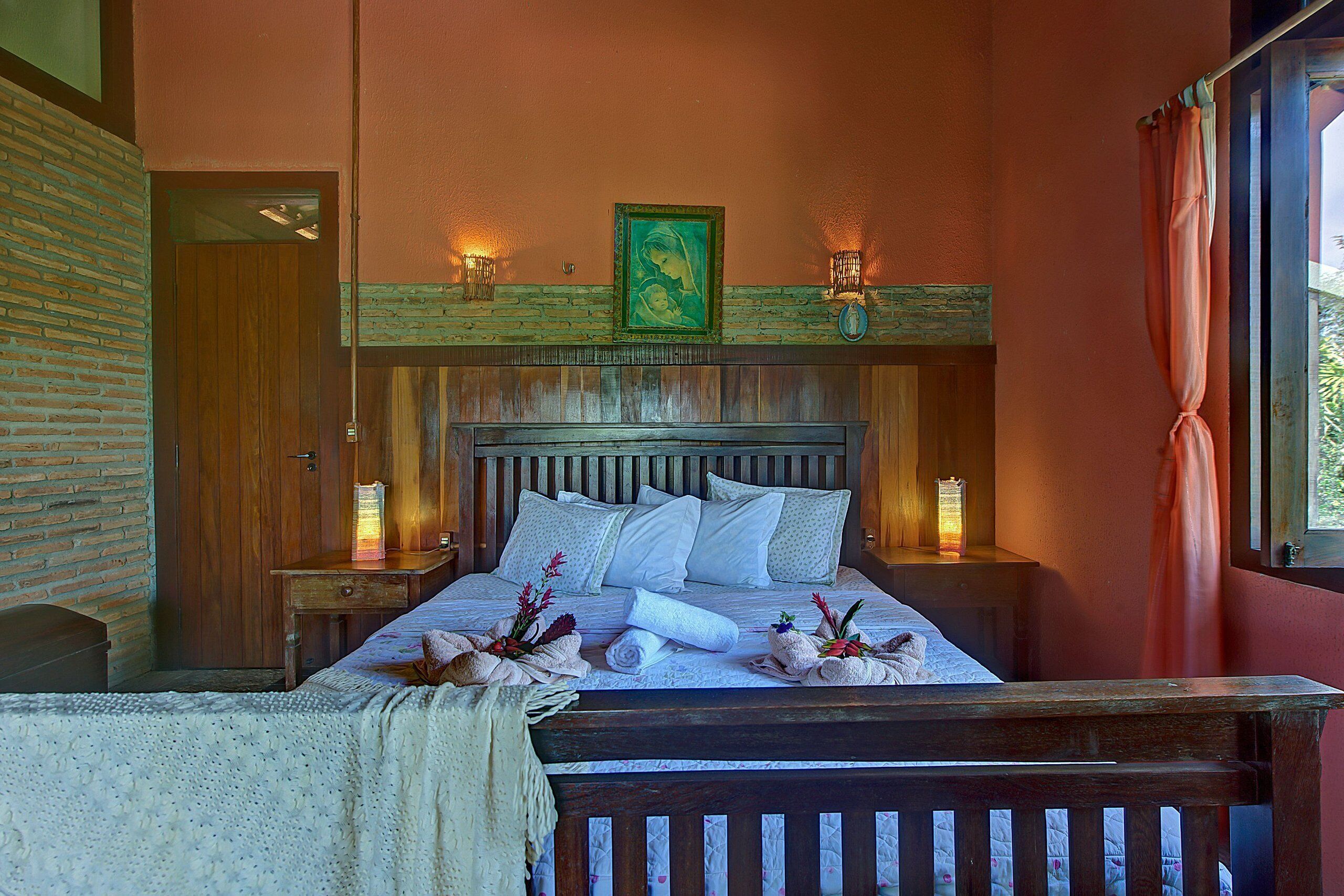 A neatly made bed with white linens and pillows, a wooden headboard, and a framed picture above.