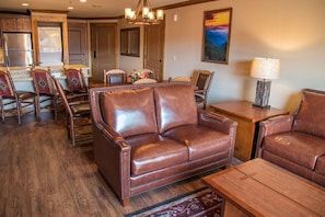 A living room with a brown leather sofa, wooden coffee table, and matching chairs.