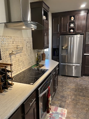 A modern kitchen with dark wooden cabinets, stainless steel appliances, and a tiled backsplash.