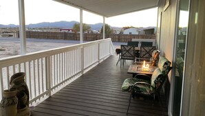 A covered outdoor patio with a table and chairs, a fire pit, and a view of the surrounding landscape. - 10 acres, for dirtbikes+ near Death Valley, casinos and wineries, Stargazing ect (Pahrump)