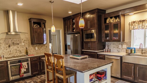 A modern kitchen with dark wood cabinets, stainless steel appliances, and a central island with bar stools. - 10 acres, for dirtbikes+ near Death Valley, casinos and wineries, Stargazing ect (Pahrump)