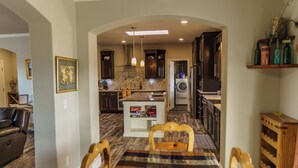 A spacious kitchen with dark wooden cabinets, a central island, and a dining area with a plaid tablecloth. - 10 acres, for dirtbikes+ near Death Valley, casinos and wineries, Stargazing ect (Pahrump)