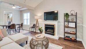 Una sala de estar con chimenea, televisor y estantería.