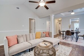 A living room with a sectional sofa, a round coffee table, and a ceiling fan. - Boho-Inspired Townhome by Masters! (Augusta)