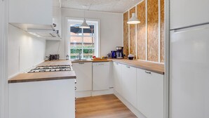 A modern kitchen with white cabinetry, a wooden countertop, a gas stove, a coffee maker, and a window with a view of greenery. - Amazing home in Tranekær with WiFi (Tranekær)