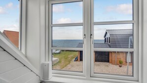 A window with a view of a building with a tiled roof and a grassy area with a small structure. - Amazing home in Tranekær with WiFi (Tranekær)
