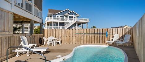 A pool area with lounge chairs and a wooden deck.
