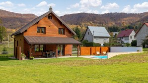 Une cabane en bois dotée d’une terrasse, d’une piscine et offrant une vue sur une chaîne de montagnes boisées.