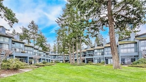 A modern apartment complex with multiple buildings, a well-maintained lawn, and mature trees.