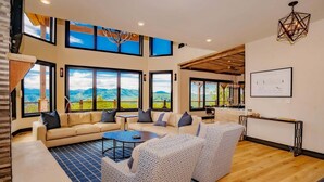 A spacious living area with large windows, a high ceiling, and a view of mountains. - Manna Mountain Lodge ~  Indoor Pool, XBox Room, Gaming Garage, Views & More! (Sevierville)