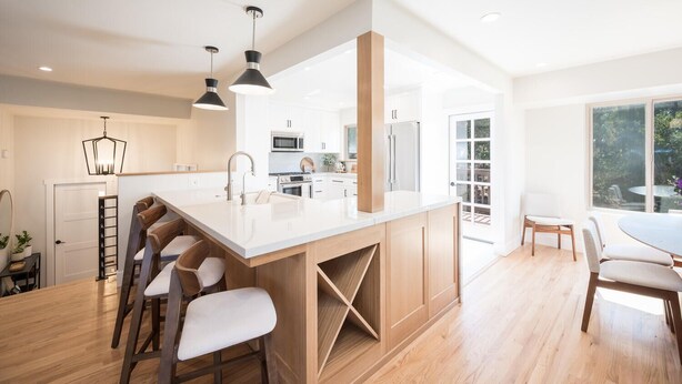 A modern kitchen with a large island, wooden bar stools, and pendant lighting. - Mid-Century Retreat Overlooking the Pines & Pacific (Cambria)