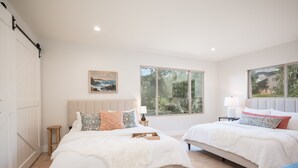 A bedroom with two beds, a wooden floor, a painting, and large windows. - Mid-Century Retreat Overlooking the Pines & Pacific (Cambria)