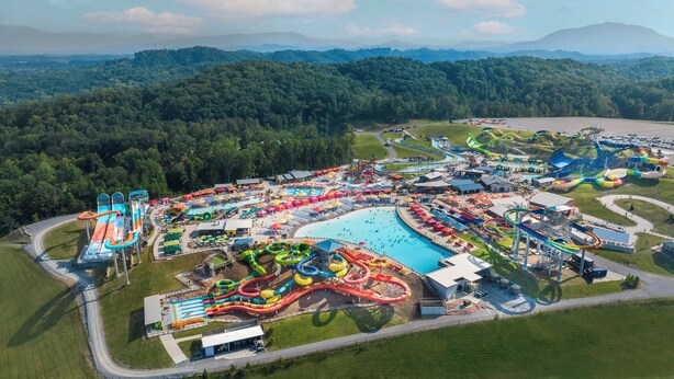 An aerial view of a water park with multiple slides and pools, surrounded by forested hills. - 3 Miles to Pigeon Forge Parkway! Private Pool 🏊‍♂️ Hot Tub 🐕 Dogs 🏔️ GSMNP Views 🌄 (Sevierville)