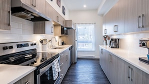 Una cocina moderna con electrodomésticos de acero inoxidable, armarios de madera y un amplio ventanal que proporciona luz natural.