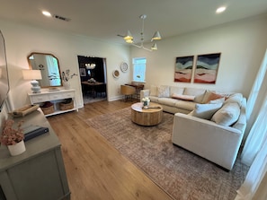 A living room with a sofa, coffee table, and a dining area with a table and chairs. - ❤️2.2 MilesToLSU•2 Desks•WasherDryer•AC🤿Pool•FencedYardPatio📺SmartTV❤️ (Baton Rouge)