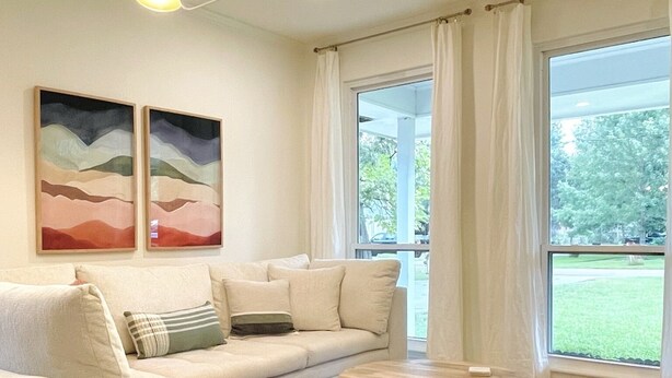 Uma sala de estar moderna com um sofá seccional, uma mesa de centro redonda e duas pinturas na parede.