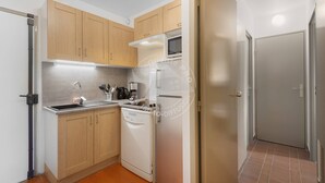 Une cuisine compacte avec des meubles en bois, un four à micro-ondes encastré et un lave-vaisselle.