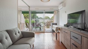 Un salon moderne comprenant un canapé, un téléviseur et un coin repas avec une table et des chaises.