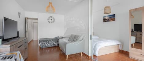 A modern bedroom with a bed, a TV, a sofa, and a dining area.