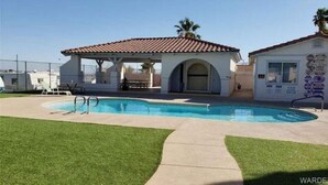 A swimming pool with a covered area, a small building with a tiled roof, and a grassy lawn. - Fun Rustic 2/2 Single level in a great community. (Laughlin)