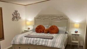 A bedroom with a bed, nightstands, a wall-mounted lamp, and a wooden floor. - Fun Rustic 2/2 Single level in a great community. (Laughlin)