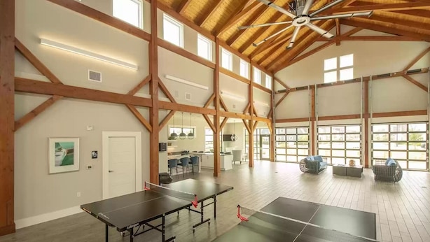 A spacious room with high ceilings, wooden beams, and large windows. - Beautiful Beau Coast Home w/ Pool, Bikes, EV Charger & Dock Access (Beaufort)