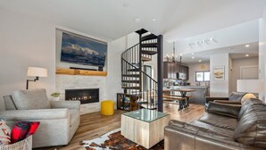 Una sala de estar moderna con chimenea, una mesa de centro de vidrio y un sofá de cuero.
