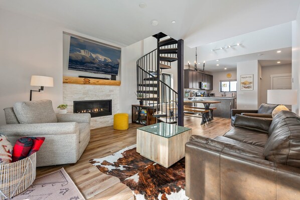 A modern living room with a fireplace, a glass coffee table, and a leather sofa.