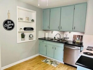A kitchen with teal cabinets, a stainless steel sink, and a dishwasher.