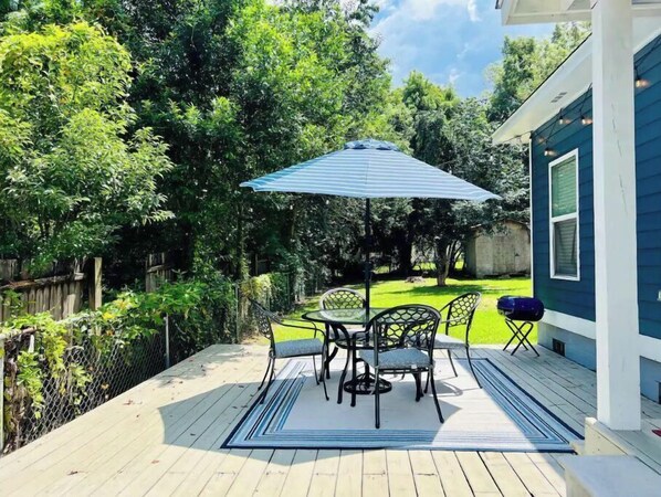 Relax in a serene outdoor setting with a table and chairs under a shaded umbrella.