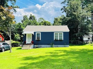 Stroll up to this charming home, featuring a cozy front porch and a beautifully manicured lawn.