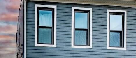 Una casa de dos pisos con puerta principal marrón, varias ventanas y un pequeño porche.