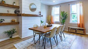 A dining area with a wooden table, white chairs, and a decorative mirror on the wall.