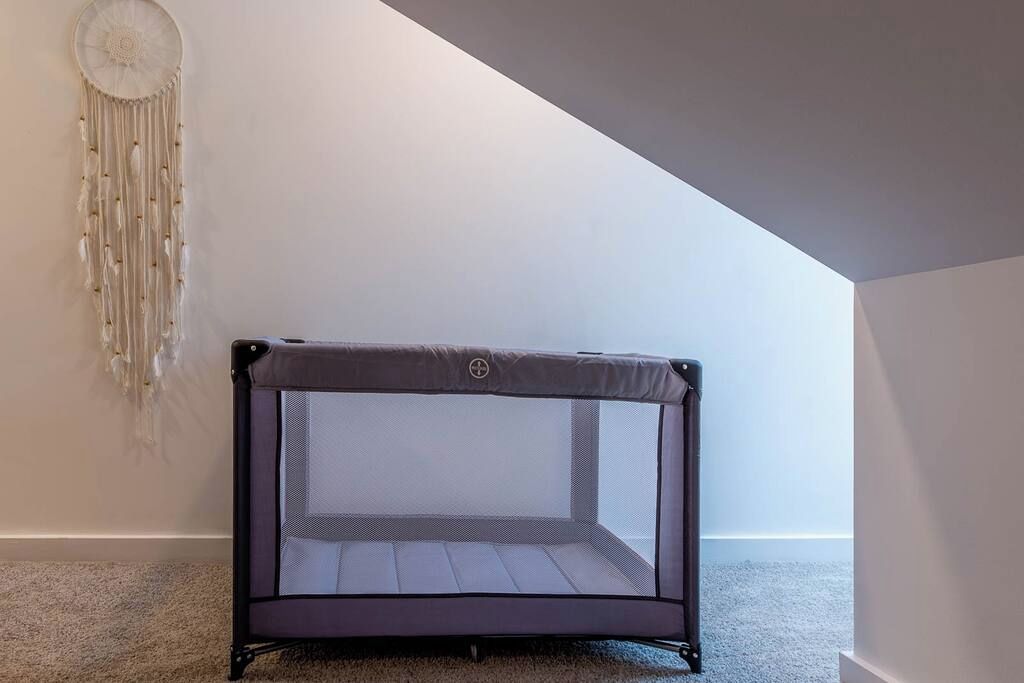 Una habitación con un trampolín en el centro, un atrapasueños en la pared y un techo inclinado.