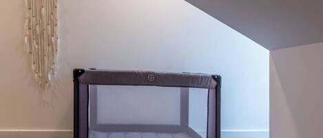 Una habitación con un trampolín en el centro, un atrapasueños en la pared y un techo inclinado.
